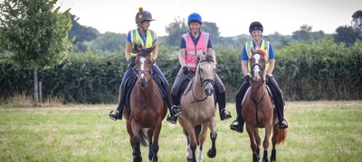three smiling riders on horses