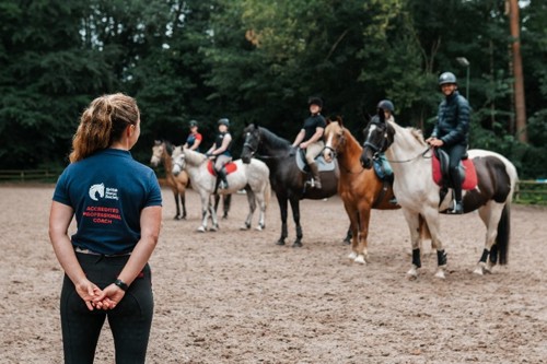 Woman in an APC polo shirt taking a group lesson in an arena