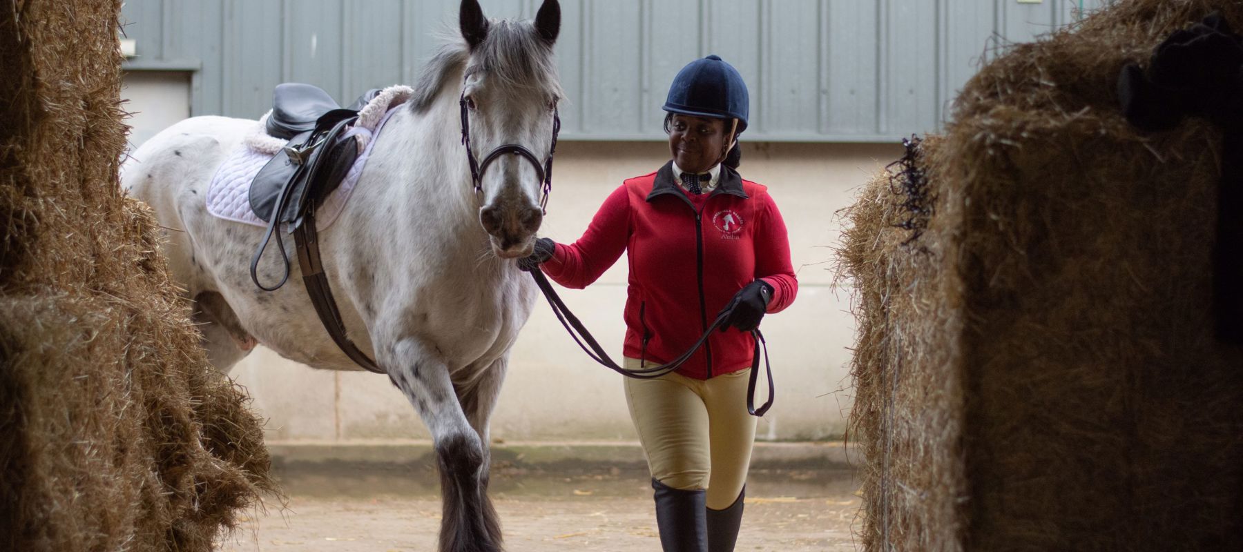 rider with horse near hay