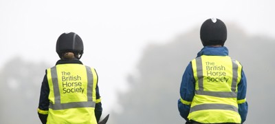 two riders on horses wearing BHS hi vis