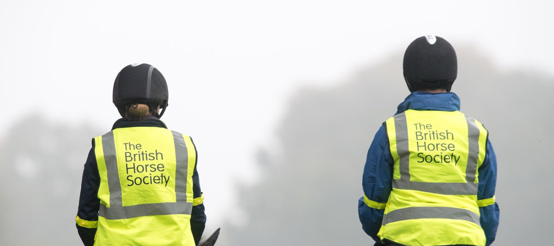 two riders on horses wearing BHS hi vis