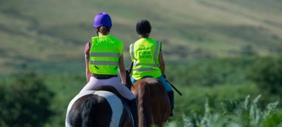 two riders on horses wearing BHS hi vis