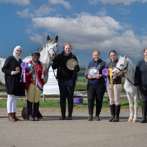 horse riders with horses showing rosettes